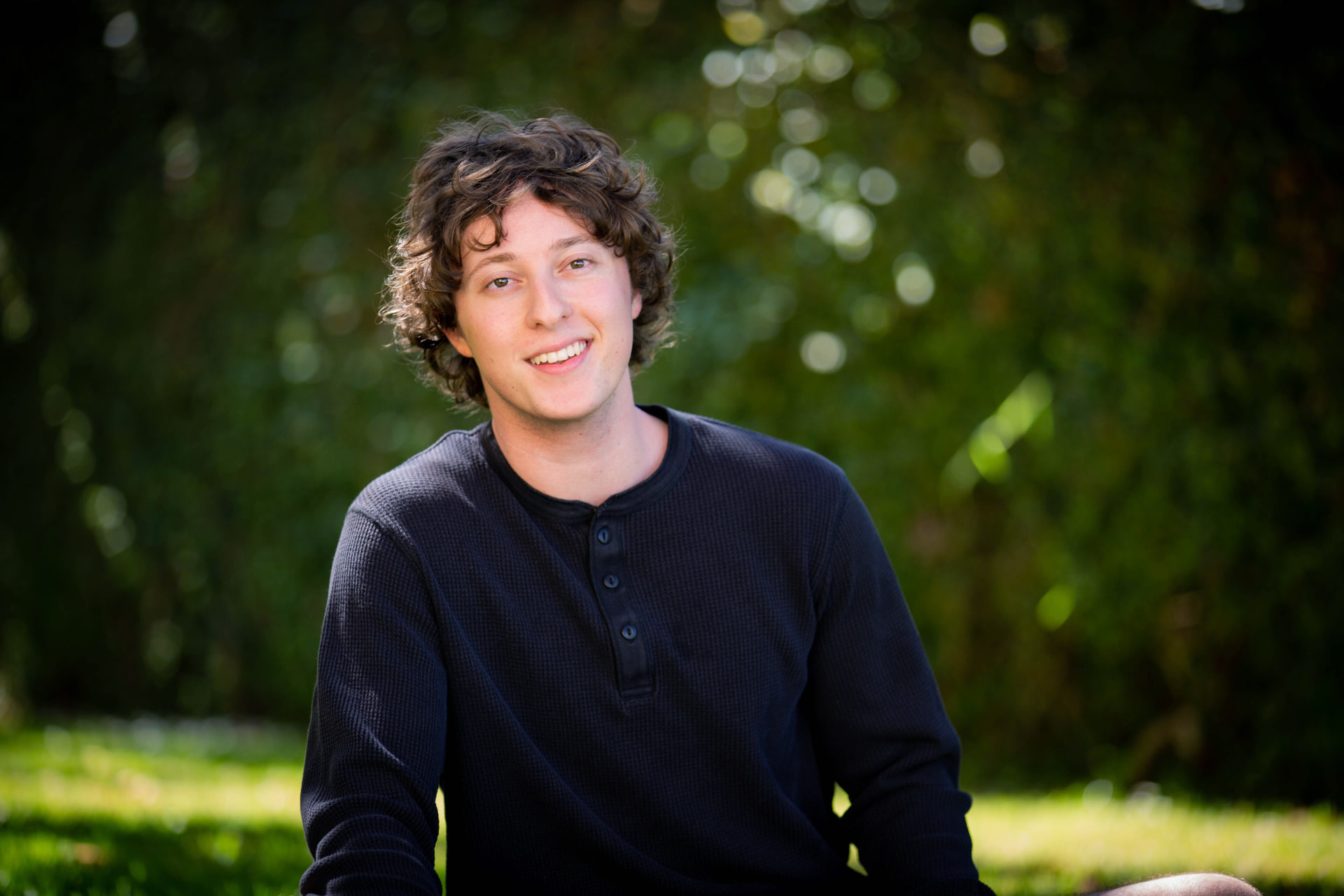 Sam Rubin smiling outdoors against a green garden background